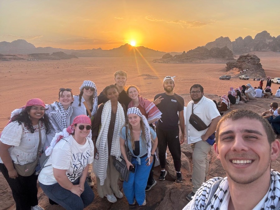 A group of students pose for a selfie in the Jordanian Desert at sunset